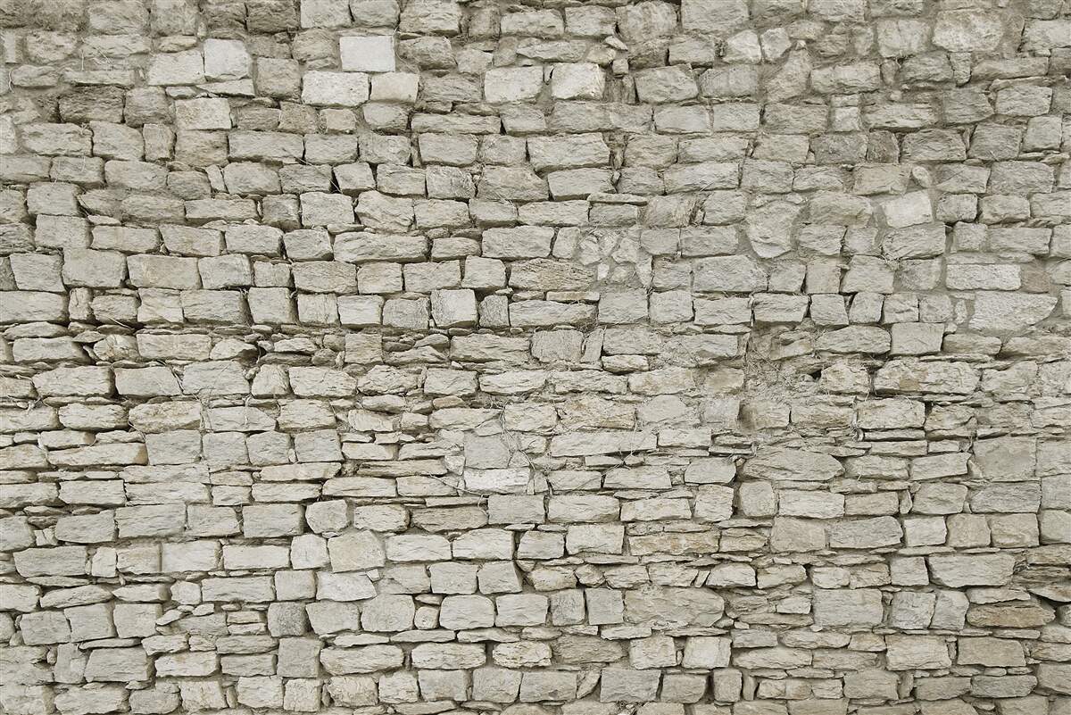 Fotobehang verspreide stenen muur leggen