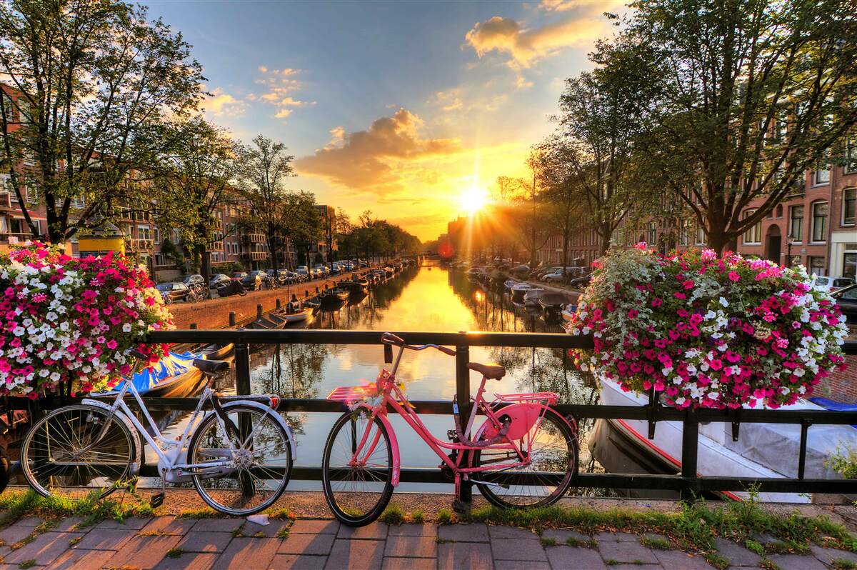 Fotobehang zonsondergang in amsterdam met fietsen op de achtergrond