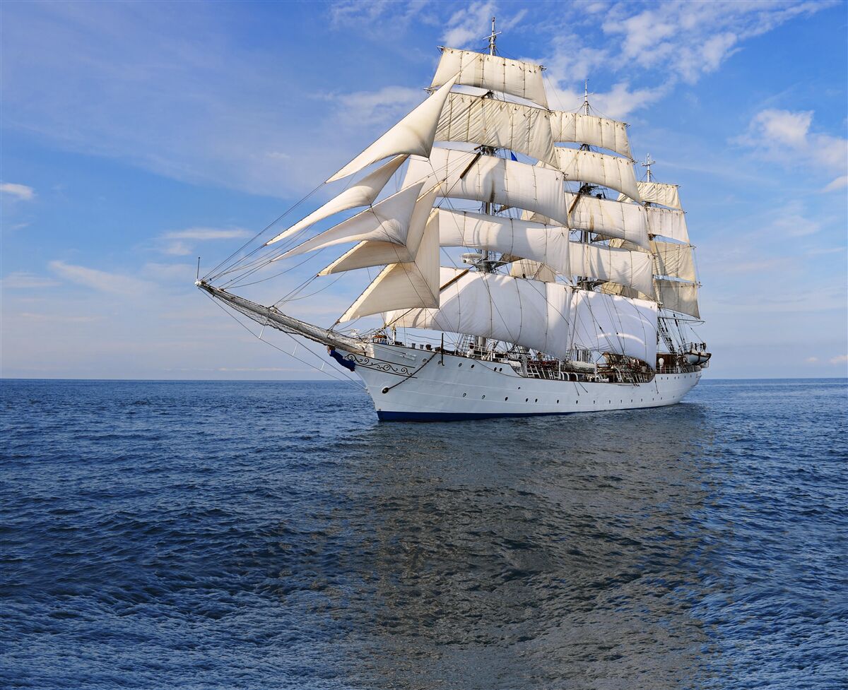 Fotobehang een schip met zeilen op een kalme zee