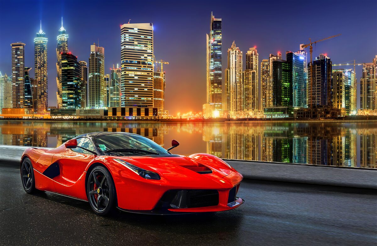 Fotobehang sportwagen met een nachtelijk stadslandschap op de achtergrond