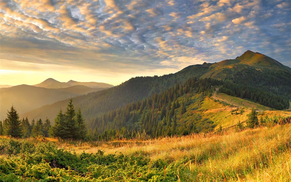 Fotobehang de wolken boven de bergen zijn geschilderd in de warme kleuren van de zonsondergang