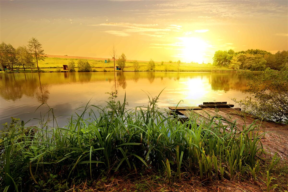 Fotobehang heldere zonsopgang boven een rustig meer