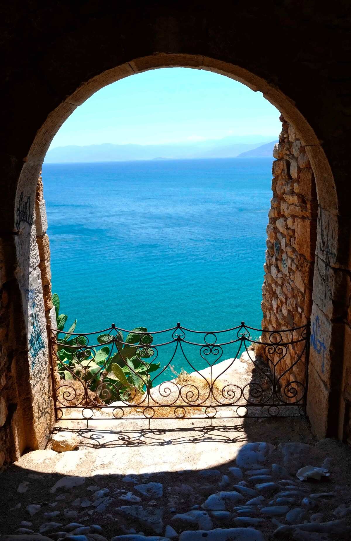 Fotobehang stenen boog die naar de zee leidt