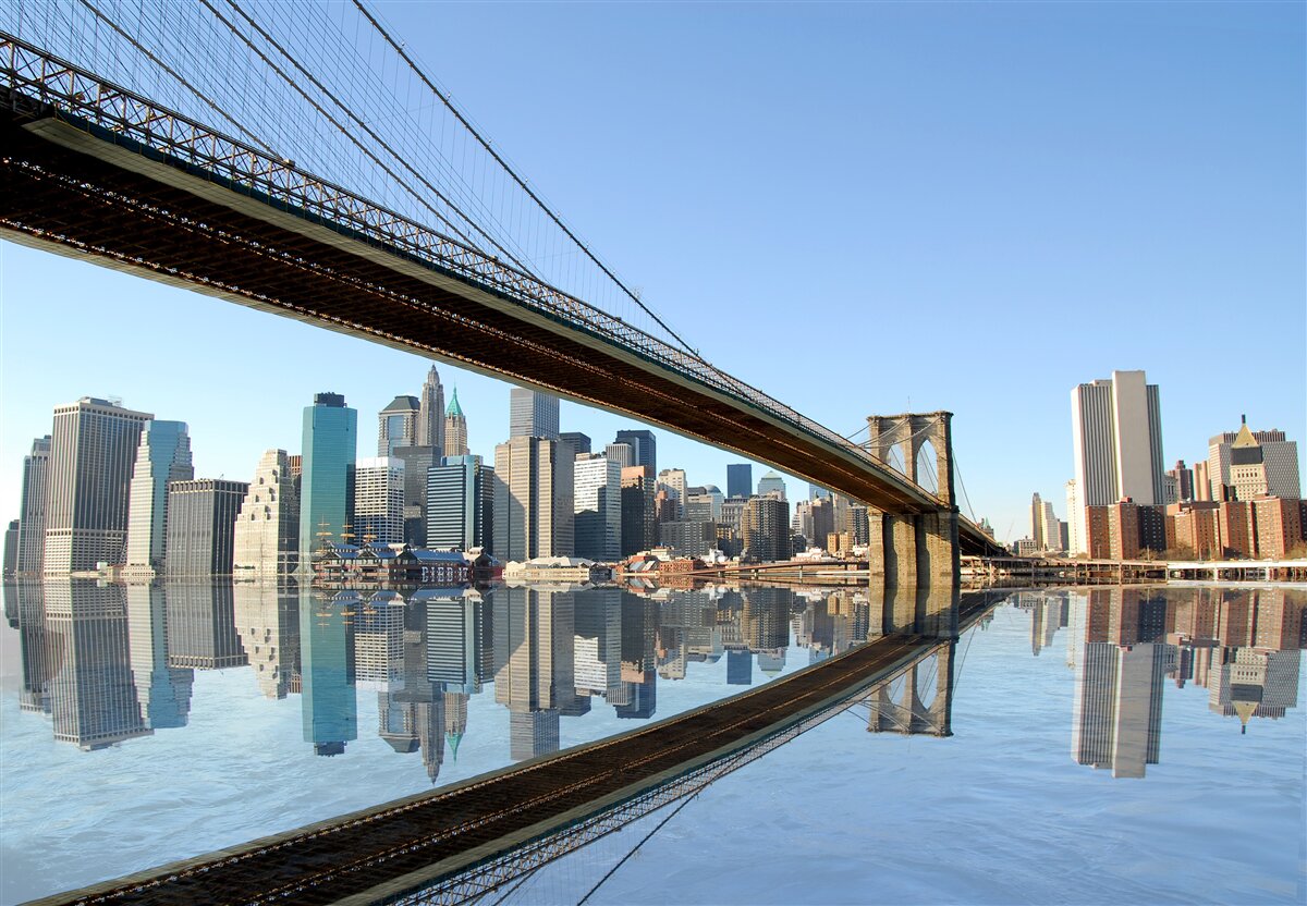 Fotobehang een brug over een rivier die naar een grote stad leidt