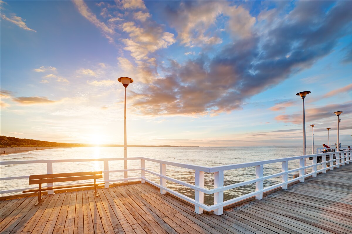 Fotobehang verlaten houten pier ziet de zon bij zonsondergang