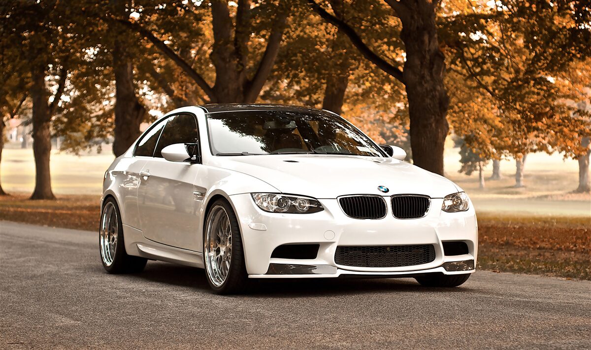 Fotobehang een witte bmw rijdt over de weg in de herfst