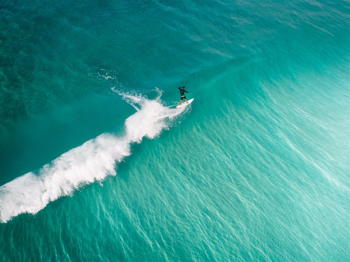 Fotobehang een eenzame surfer in de uitgestrektheid van de oceaan